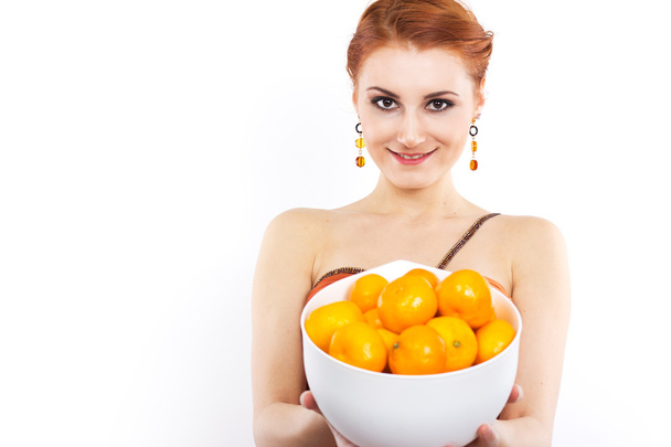Jeune fille aux cheveux roux avec des mandarines en robe de soirée. Portrait d'une fille dans une longue robe orange
. - Photo, image