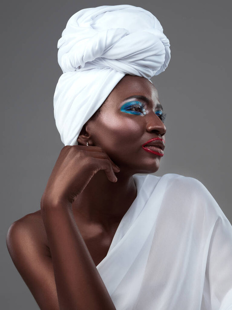 Знойная тишина африканской красоты. Студийный снимок привлекательной молодой женщины, позирующей в традиционной африканской одежде на сером фоне - Фото, изображение