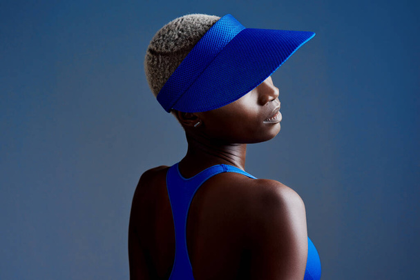 Living life on the sporty side. Studio shot of a sporty young woman wearing a visor while posing against a blue background - Valokuva, kuva