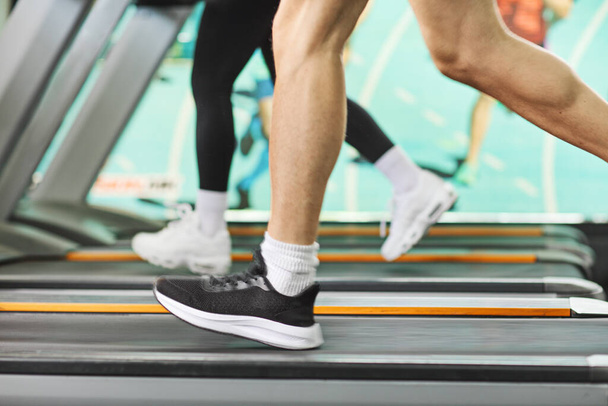 Shot of male and female legs running on treadmills in a gym - Photo, image