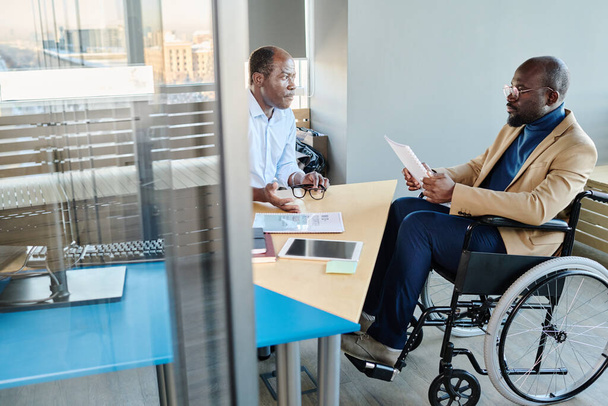 Αυτοπεποίθηση αφεντικό ακούει την αναφορά του υφισταμένου του σε αναπηρική καρέκλα, σχολιάζει, κάνει ερωτήσεις διευθυντής και τον συμβουλεύεται - Φωτογραφία, εικόνα