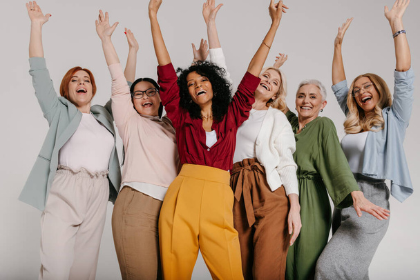 Многонациональная группа счастливых зрелых женщин, жестикулирующих и улыбающихся на сером фоне - Фото, изображение