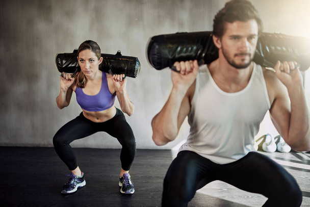 Las excusas no queman calorías. dos jóvenes haciendo ejercicio en el gimnasio usando bolsas pesadas - Foto, imagen