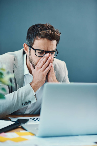 ¿Por qué este portátil sigue estrellándose. un joven hombre de negocios que parece estresado mientras trabaja en un portátil en una oficina - Foto, Imagen