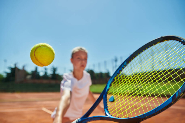 Close up photo of a young girl showing professional tennis skills in a competitive match on a sunny day, surrounded by the modern aesthetics of a tennis court - Fotografie, Obrázek