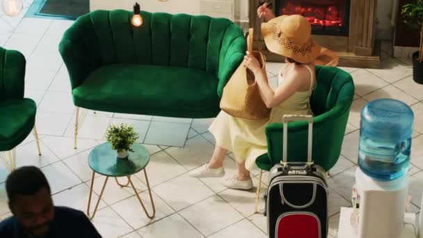 Bellboy segít női vendég cipelni poggyász a szobájába, utazó targonca táskák vár a társalgóban. Professzionális londíner luxus szolgáltatást nyújt a hotel ügyfeleinek. Kézi lövés.. - Felvétel, videó