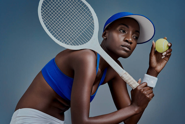 Tenis to coś więcej niż sport. Studyjne ujęcie sportowej młodej kobiety pozującej ze sprzętem do tenisa na szarym tle - Zdjęcie, obraz