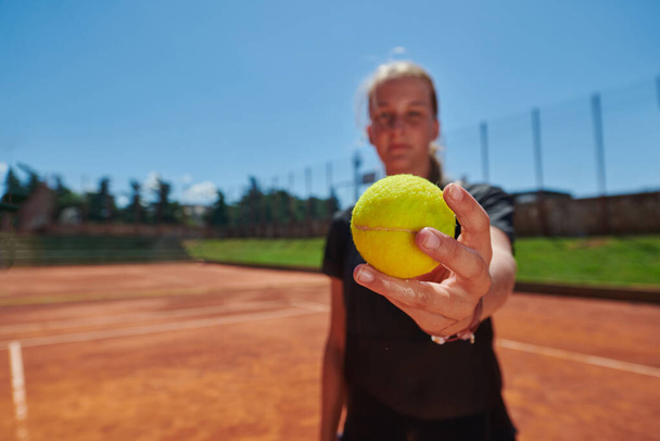 Before her training, the tennis player joyfully playing with a tennis ball, radiating enthusiasm and playfulness, as she prepares herself mentally and physically for the upcoming challenges on the - Foto, Imagen
