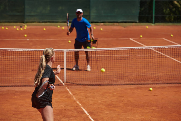 A professional tennis player and her coach training on a sunny day at the tennis court. Training and preparation of a professional tennis player. - Foto, Imagen