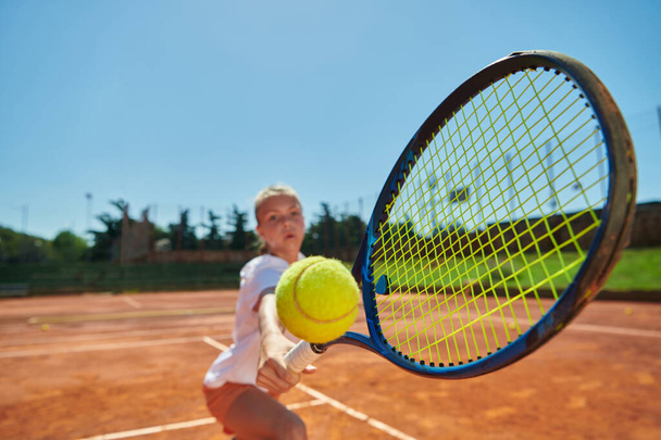 Güneşli bir günde tenis kortunun modern estetiğiyle çevrili profesyonel tenis yeteneklerini sergileyen genç bir kızın yakın plan fotoğrafı. - Fotoğraf, Görsel