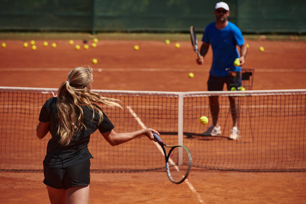 A professional tennis player and her coach training on a sunny day at the tennis court. Training and preparation of a professional tennis player. - Zdjęcie, obraz
