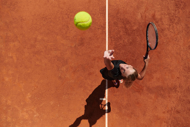 Top view of a professional female tennis player serves the tennis ball on the court with precision and power.  - Fotó, kép
