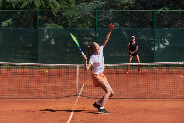 Fiatal lányok egy élénk tenisz mérkőzés egy napsütéses napon, bemutatva képességeiket és lelkesedésüket a modern teniszpályán - Fotó, kép