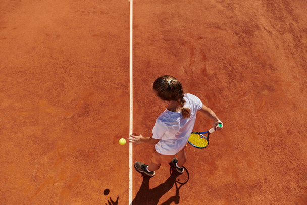 Top view of a professional female tennis player serves the tennis ball on the court with precision and power.  - Fotoğraf, Görsel