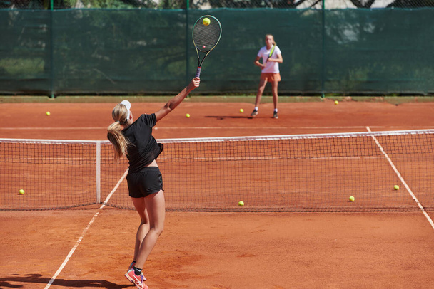 Young girls in a lively tennis match on a sunny day, demonstrating their skills and enthusiasm on a modern tennis court - Photo, image