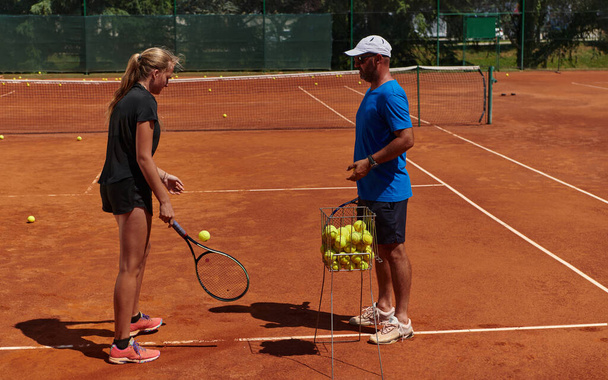 A professional tennis player and her coach training on a sunny day at the tennis court. Training and preparation of a professional tennis player. - Фото, изображение