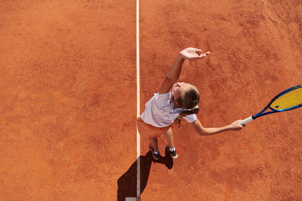 Top view of a professional female tennis player serves the tennis ball on the court with precision and power.  - Fotoğraf, Görsel