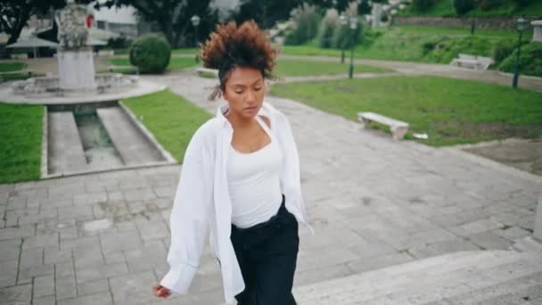 Sebevědomá zpěvačka tančí stylově na schodech do parku. Trendy cool africká americká dívka pohybující se tělo svůdně praktikující sexy tanec zpomalený film. Módní dáma hraje jazzovou choreografii - Záběry, video