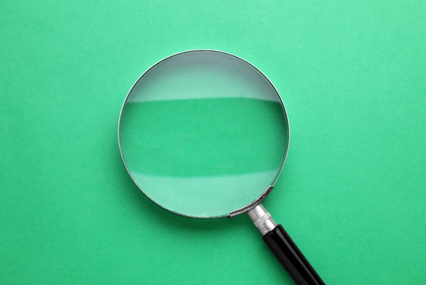 Magnifying glass on green background, top view - Fotoğraf, Görsel