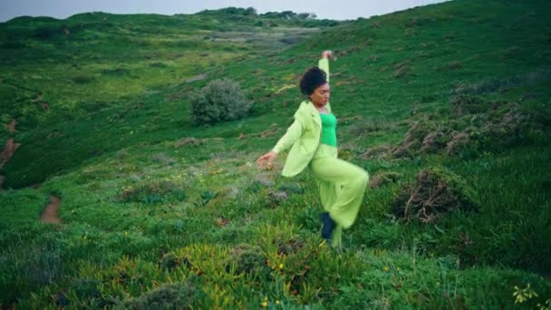 Expresiva mujer afroamericana bailando en un campo nublado. Bailarina profesional enfocada realizando estilo contemporáneo sobre hierba verde. Artista apasionado practicando improvisación danza al aire libre. - Metraje, vídeo