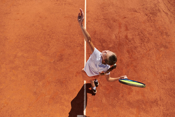 Top view of a professional female tennis player serves the tennis ball on the court with precision and power.  - Foto, Bild