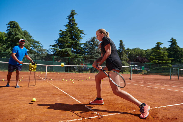 A professional tennis player and her coach training on a sunny day at the tennis court. Training and preparation of a professional tennis player. - Valokuva, kuva