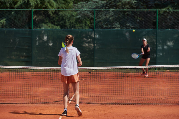Young girls in a lively tennis match on a sunny day, demonstrating their skills and enthusiasm on a modern tennis court - Foto, Imagem