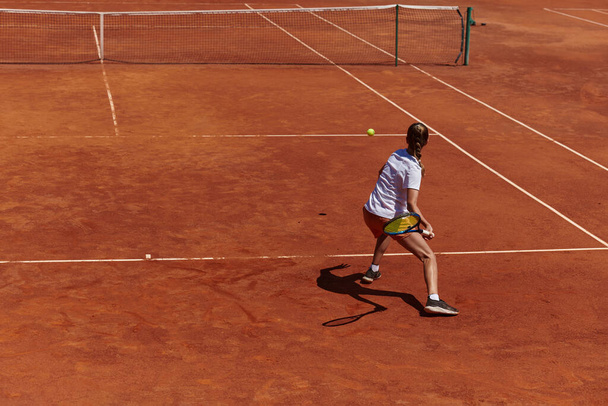 A young girl showing professional tennis skills in a competitive match on a sunny day, surrounded by the modern aesthetics of a tennis court - Foto, immagini