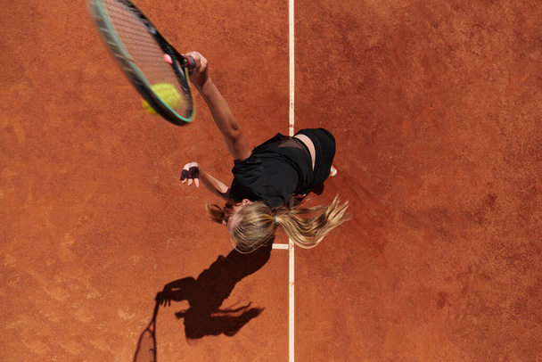 Top view of a professional female tennis player serves the tennis ball on the court with precision and power.  - Fotografie, Obrázek