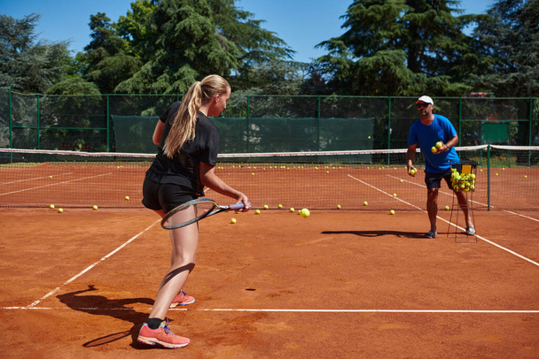 A professional tennis player and her coach training on a sunny day at the tennis court. Training and preparation of a professional tennis player. - Valokuva, kuva