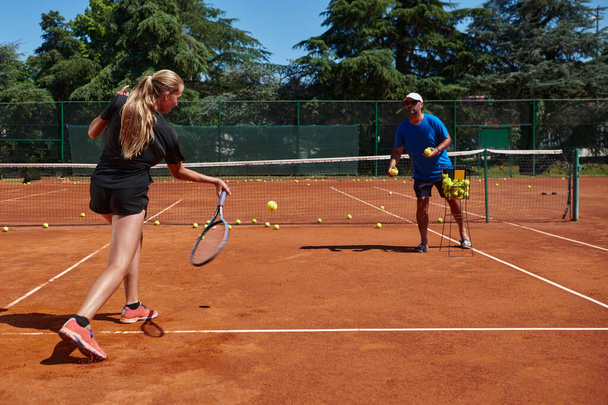A professional tennis player and her coach training on a sunny day at the tennis court. Training and preparation of a professional tennis player. - Фото, зображення