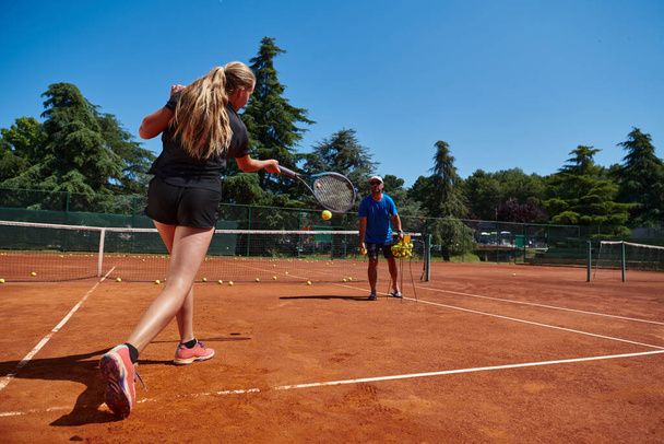 A professional tennis player and her coach training on a sunny day at the tennis court. Training and preparation of a professional tennis player. - Фото, изображение