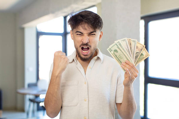 young handsome man looking angry, annoyed and frustrated. dollar banknotes concept - 写真・画像