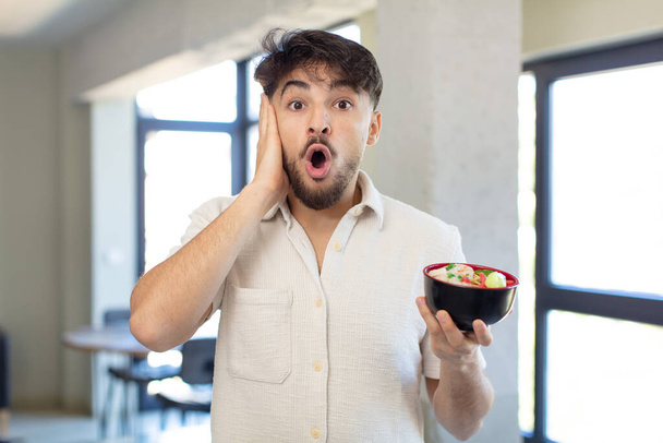 young handsome man feeling extremely shocked and surprised.  ramen japanese noodles concept - Foto, Bild