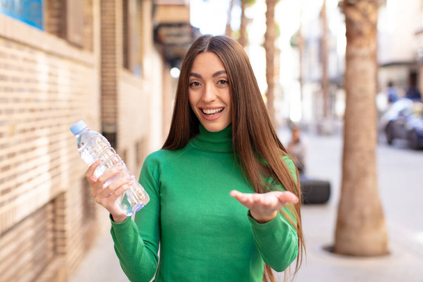 smiling happily and offering or showing a concept. water bottle concept - Photo, image