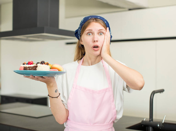 young pretty woman feeling extremely shocked and surprised. home made cakes concept - Foto, Bild