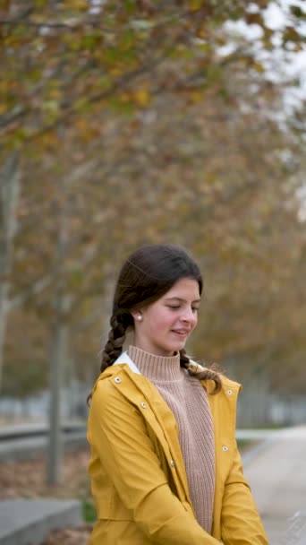Портрет девочки-подростка в желтом дождевике, открывающей зонтик, улыбающейся и смотрящей в камеру на улице осенью. - Кадры, видео