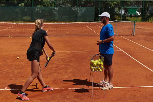 Una tenista profesional y su entrenador entrenando en un día soleado en la cancha de tenis. Formación y preparación de un tenista profesional. - Foto, Imagen