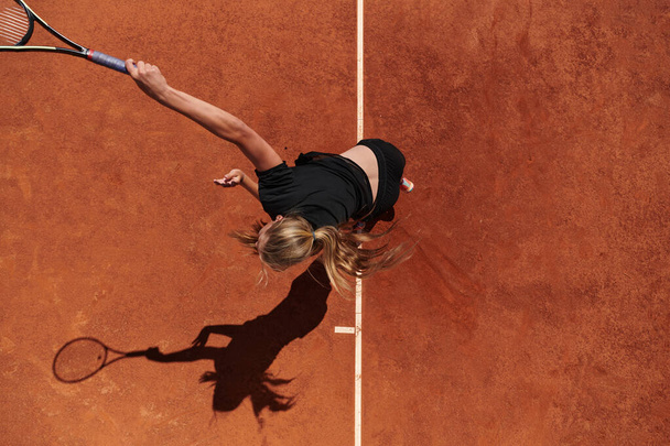 Top view of a professional female tennis player serves the tennis ball on the court with precision and power.  - Φωτογραφία, εικόνα