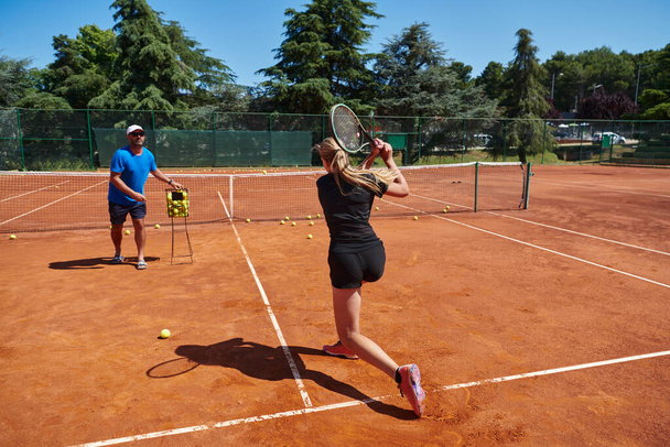 A professional tennis player and her coach training on a sunny day at the tennis court. Training and preparation of a professional tennis player. - Photo, Image