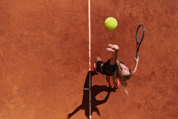 Top view of a professional female tennis player serves the tennis ball on the court with precision and power.  - Photo, Image