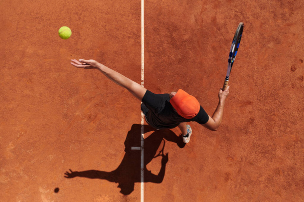 Top view of a professional tennis player serves the tennis ball on the court with precision and power.  - Foto, afbeelding
