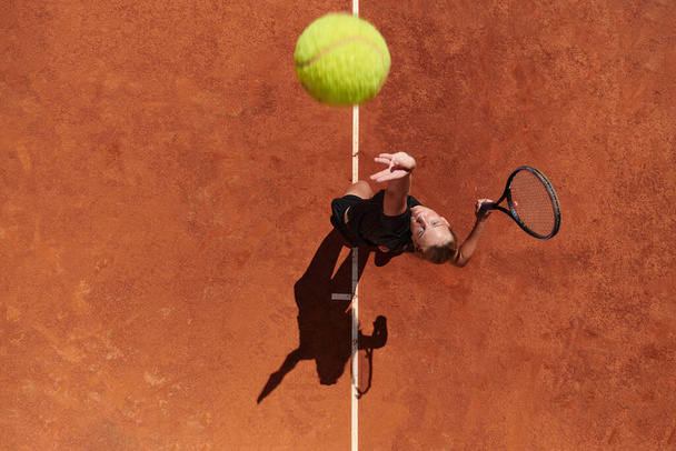Top view of a professional female tennis player serves the tennis ball on the court with precision and power.  - Foto, Imagem