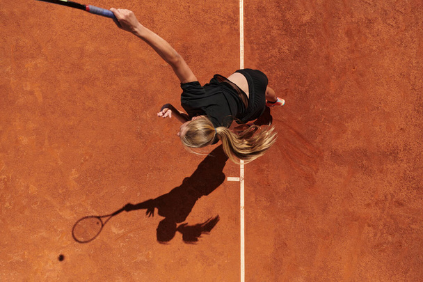 Top view of a professional female tennis player serves the tennis ball on the court with precision and power.  - Valokuva, kuva