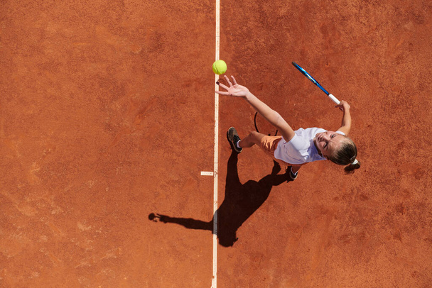 Top view of a professional female tennis player serves the tennis ball on the court with precision and power.  - Zdjęcie, obraz
