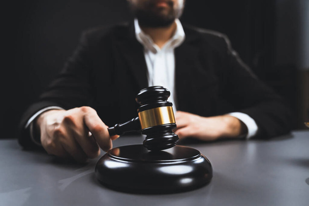 Фокус дерев'яний молоток з спаленим адвокатом у чорному костюмі, що тримає данину на фоні столу, символ правосуддя та цілісності, збалансоване та етичне рішення в суді правової рівності
 - Фото, зображення