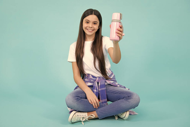 Tinédzser alkalmi viseletben tartja a vizes palackot. Hipszter tini. Boldog tinédzser, pozitív és mosolygós érzelmek tini lány - Fotó, kép