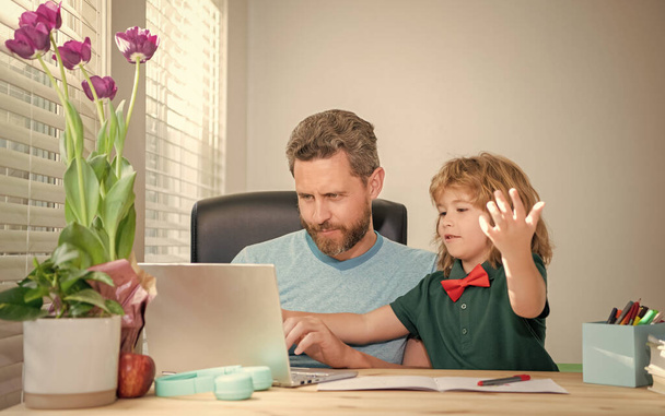 髭を生やした父や学校の家庭教師が現代のノートパソコンで息子にeラーニングを教えています. - 写真・画像