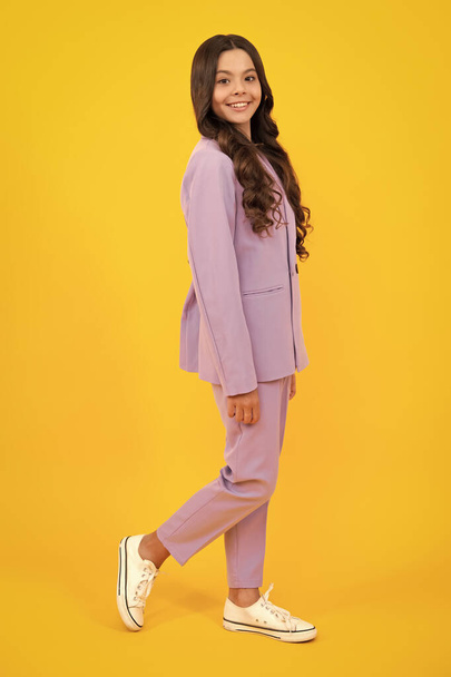 Full length photo of brunette teen girl wear casual clothes isolated on yellow background. Happy teenager, positive and smiling emotions of teen girl - 写真・画像