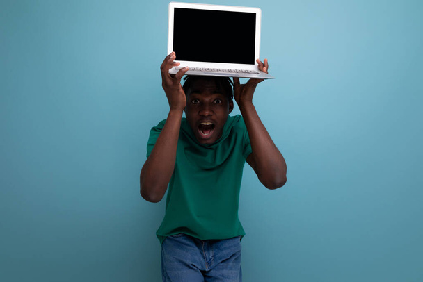 americano jovem morena homem em casual t-shirt mostra tela do laptop com mockup para página da web. - Foto, Imagem